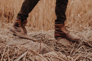 Man wearing brown boots with jeans in a rugged terrain