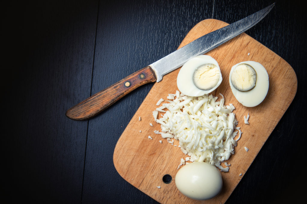 Knife on cutting board with an egg cut in half