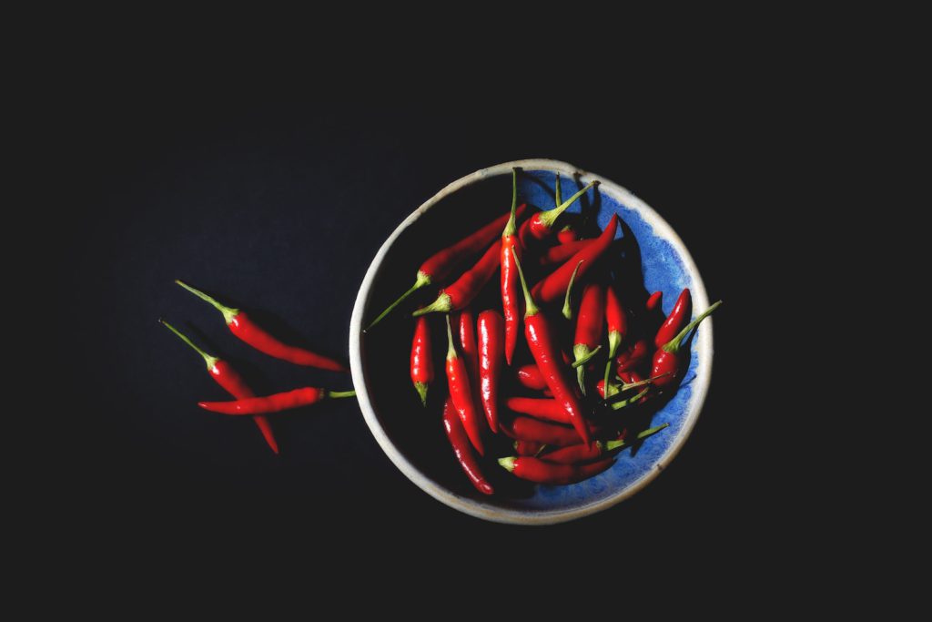 Bowl of red chili peppers on black background
