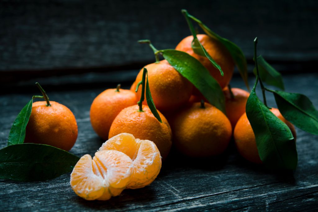 a bunch of mandarin oranges on a wooden surface