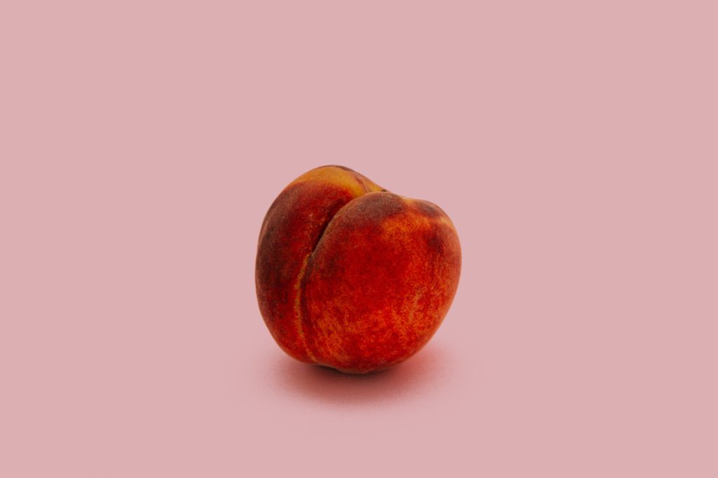 single peach on a pink background