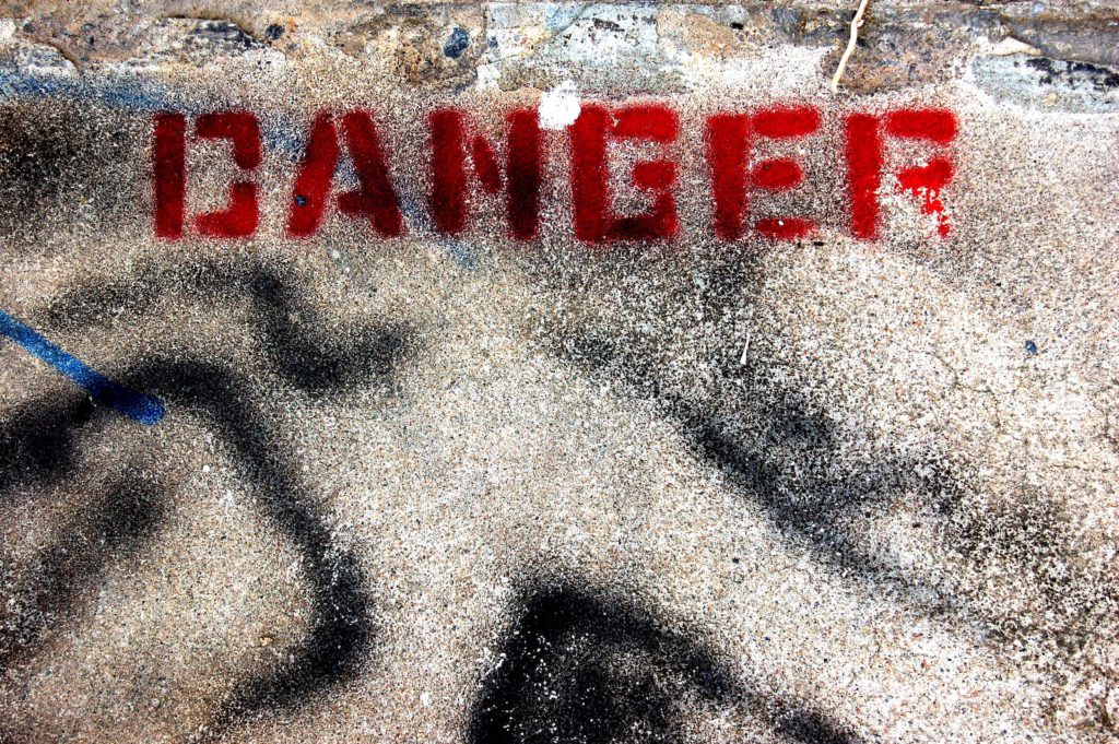 The word DANGER spray painted on the pavement. 