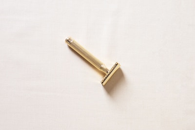 A gold safety razor on a white surface