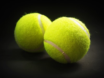 Two tennis balls on a black surface