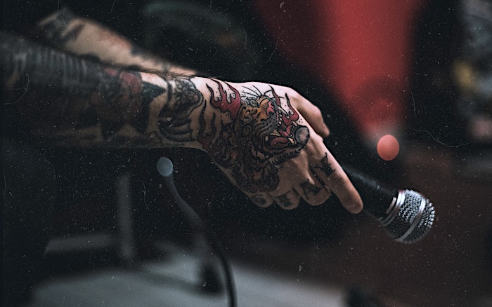 A tattooed hand holding a microphone