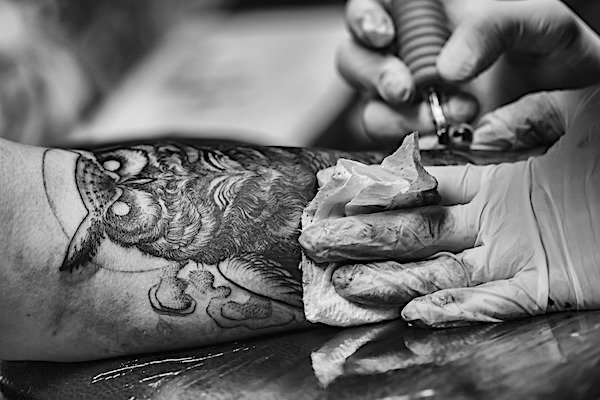 A black and gray scale owl tattoo being worked on