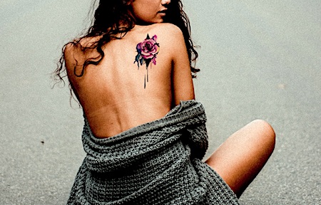 A bright colored rose tattoo on a woman's back
