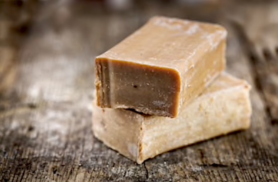 2 bars of handmade soap resting on a wooden surface