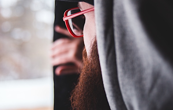 Man with a beard looking out of the window