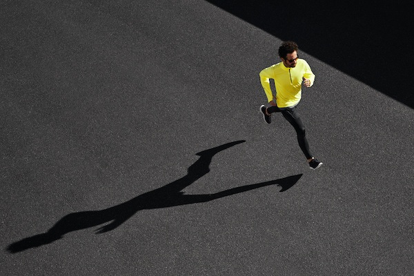 Man running in the street wearing workout attire.
